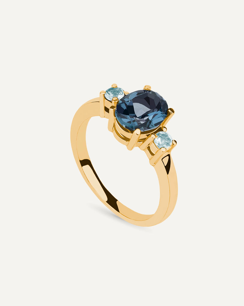 Anillo Luxe en plata de ley con baño de oro y con topacio London Blue en talla oval y topacios Sky.